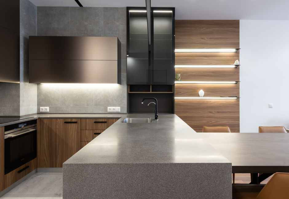 Wooden cabinets with a stove beside a gray countertop